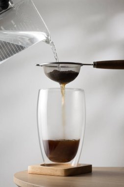 Filtering tea in cup on wooden table