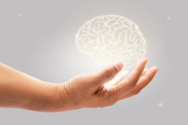 Man holding brain illustration against gray wall background. Concept with mental health protection and care.	