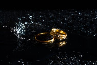 Karanlık bir arka planda yüzükler. Evlilik yüzükleri. Mücevherler. Su damlaları.