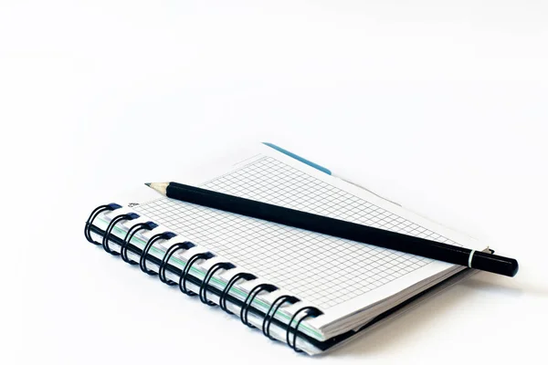 Beyaz arka planda bir kağıt parçasına kalem. Kalem ve defter. Yakın plan. Boşluğu kopyala