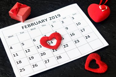 Takvim sayfasında kırmızı kalpler ve 14 Şubat 'ta bir hediye, siyah arkaplanda Sevgililer Günü. Valentine kartı..