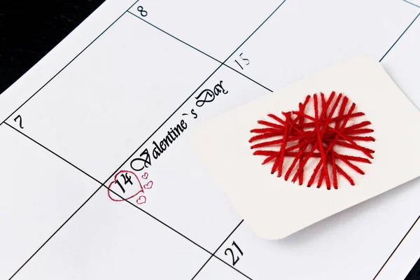 14 Şubat 'ta kırmızı kalplerle takvim sayfası, siyah arkaplanda sevgililer günü. Sevgililer Günü tebrik kartı..