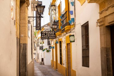 Cordoba, Endülüs, İspanya - 5 Kasım 2021: Eski kasabada balkon, tabela ve fenerli evlerin olduğu dar bir kaldırım taşı caddesi manzarası