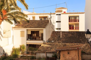 Sıcak bir günde İspanya 'nın eski Altea kasabasında fayanslı çatısı ve balkonu olan beyaz evleri ve bir palmiye ağacını görmek..