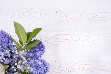 Üzerinde mavi sümbül çiçekleri olan bahar kompozisyonu beyaz, beyaz, ahşap bir masa üzerinde. Düz yatıyordu. Metin için alanı kopyala