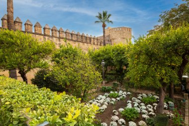 Cordoba, Endülüs, İspanya - 3 Kasım 2021: Alcazar de los Reyes Cristianos bahçeleri. Taş bir duvar ve meyve ağaçları ve çiçeklerle çevrili bir kule..