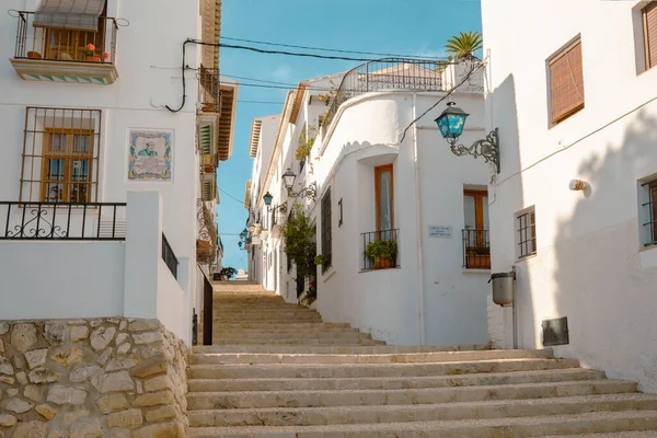 Hermosa calle estrecha con escaleras de adoquines en un casco antiguo con casas blancas y techos de azulejos. Altea, España — Foto de Stock