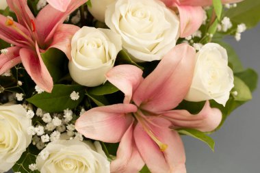 A beautiful bouquet of pink lilies and white roses on background is a blank for congratulations or invitations