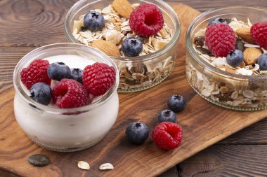 Fındıklı ev yapımı granola, ahududu ve yaban mersinli yoğurt, ahşap bir kırsal masada yoğurt, kopyalama alanı. sağlıklı kahvaltı