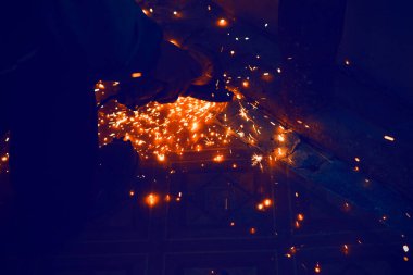 Siyah arka planda kıvılcımlar var. Öğütücüyle çalış. Karanlık odada kıvılcım saçan parçacıklar. Metal kesme