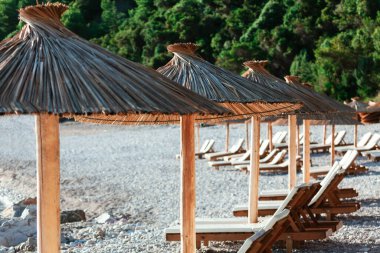 Egzotik şemsiyeli cennet kumsalı. Plaj şemsiyeleri ve çakıl taşlı plajlarda şezlonglar