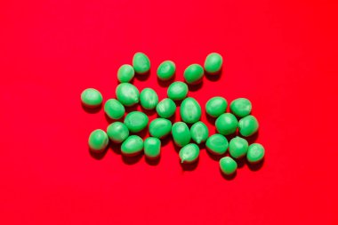 Kırmızı arka planda yeşil bezelyeler. Lifli ve proteinli bezelyeler