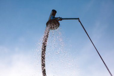 Water flows from the shower . Splashing drops of outdoor shower