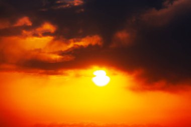 Kızıl gökyüzündeki güneş. Siyah bulutlu fantastik gün batımı