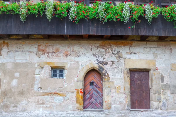 Old wall with doors . Medieval building with flower beds