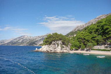 Kayalık sahili olan tropik bir sahil. Hırvatistan 'da Brela kıyısı 