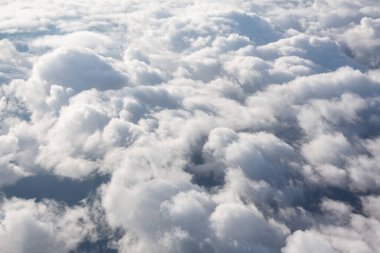 Kabarık beyaz bulutların üzerinde uçuyorlar. Bulutlarda uçan uçak 