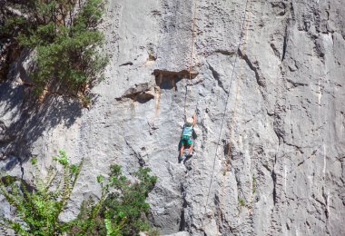 Kaya tırmanışçısı çocuk. Çocuk dağda iple tırmanıyor. 