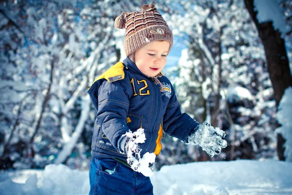 Um menino liitle que joga em um snowdrift — Fotografia de Stock