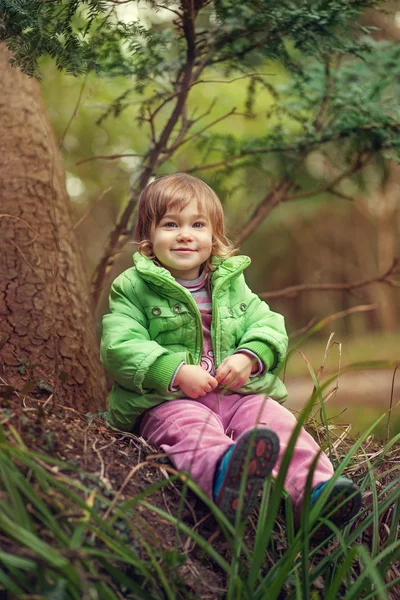 En liten flicka som sitter på det stora trädet — Stockfoto