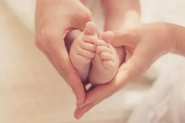 Annenin elleri closeup ayaklarda bebek — Stok fotoğraf