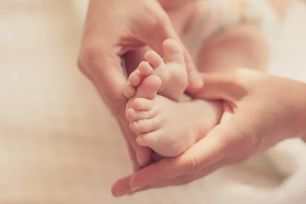 Annenin elleri closeup ayaklarda bebek — Stok fotoğraf
