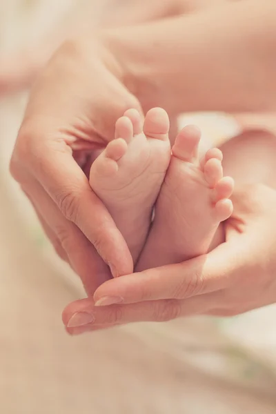 Los pies del bebé en las manos de la madre — Foto de Stock