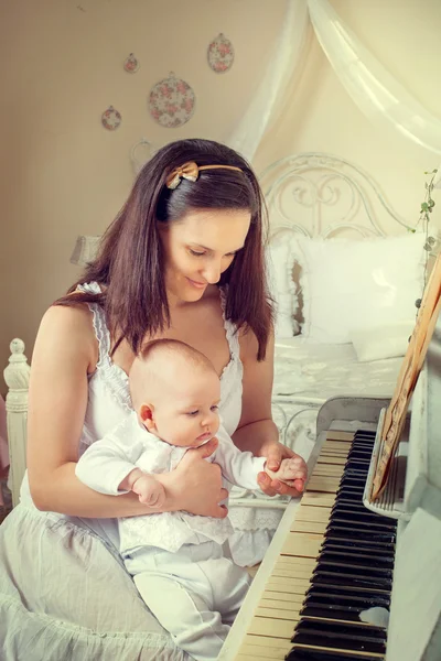 피아노 주위 신생아와 어머니 스톡 이미지