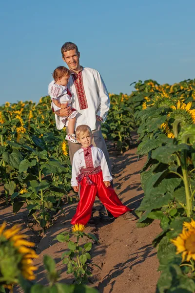 A father and two children in Ukrainian costume at sunset in a fi — Stock Photo, Image