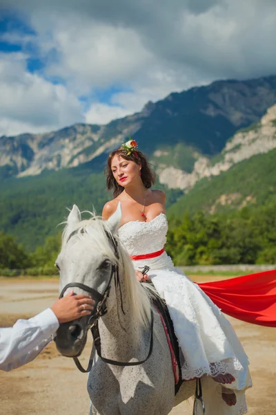 Noiva em um cavalo olha para o noivo — Fotografia de Stock