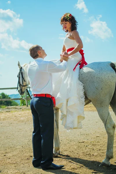 Novia en un caballo mira al novio —  Fotos de Stock