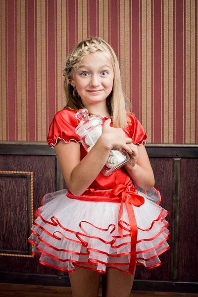 Een meisje in een rode pakje snoep in de bank — Stockfoto