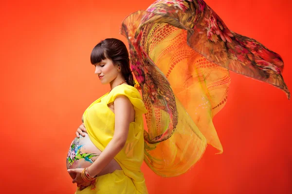 A menina grávida com o quadro desenhado em um estômago em um yello — Fotografia de Stock