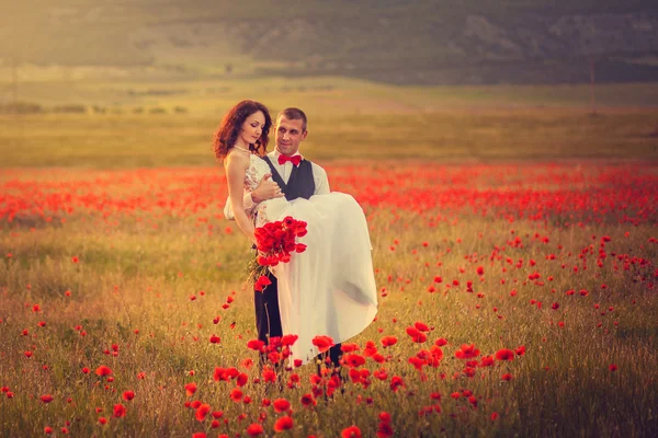 The bride and groom in a poppy field — Stock Photo, Image
