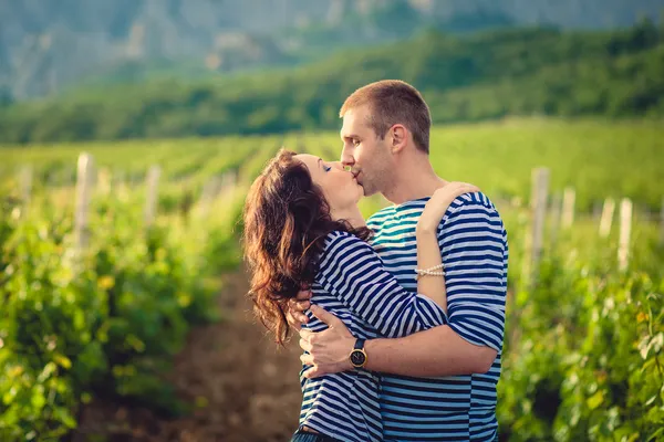 Pareja besándose en camisas a rayas en el viñedo —  Fotos de Stock