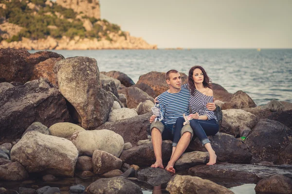 Familj i randiga tröjor på klipporna vid havet — Stockfoto