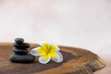 Gri ve beyaz Zen çakıl taşı piramitleri bej arka planda tropikal çiçekli meditasyon taşları. Uyum kavramı, denge ve meditasyon, spa, masaj, rahatlama