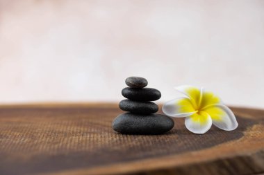 Gri ve beyaz Zen çakıl taşı piramitleri bej arka planda tropikal çiçekli meditasyon taşları. Uyum kavramı, denge ve meditasyon, spa, masaj, rahatlama