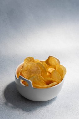 Çıtır tuzlu patates cipsi ya da beyaz arka planda kasede cips. Sağlıksız gıda konsepti.