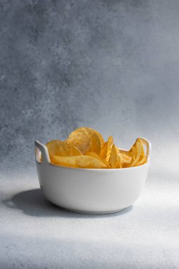 Çıtır tuzlu patates cipsi ya da beyaz arka planda kasede cips. Sağlıksız gıda konsepti.