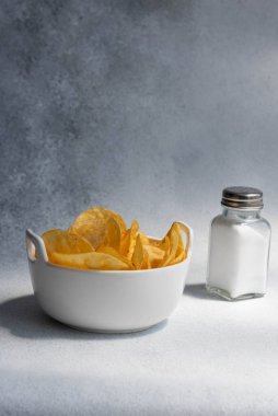 Çıtır tuzlu patates cipsi ya da beyaz arka planda kasede cips. Sağlıksız gıda konsepti.