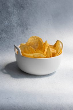 Çıtır tuzlu patates cipsi ya da beyaz arka planda kasede cips. Sağlıksız gıda konsepti.