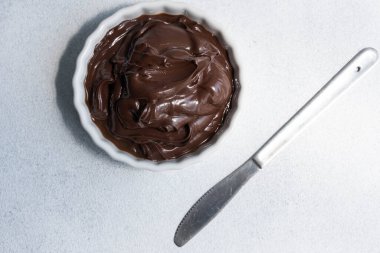 Kakao yayılmış yemek fotoğrafı. Beyaz arkaplanda beyaz çikolata parçaları olan kahverengi çikolata ezmesi..