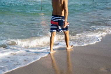 Deniz kıyısında yürüyen insanlar. Deniz ya da okyanus manzarası. Güneşin altında deniz dalgaları. Yaz tatili ve seyahat konsepti. Su dalgası yüzeyi. Kumsal. 