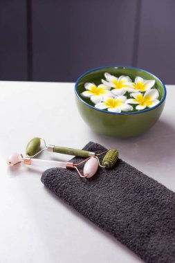 Plumeria çiçekleriyle harika bir spa kompozisyonu. Yüz silindiri ve Guasha masaj aleti. Çin Gua Sha masaj aletleri.