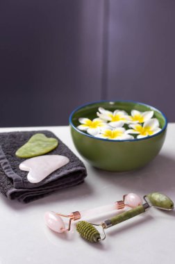 Plumeria çiçekleriyle harika bir spa kompozisyonu. Yüz silindiri ve Guasha masaj aleti. Çin Gua Sha masaj aletleri.