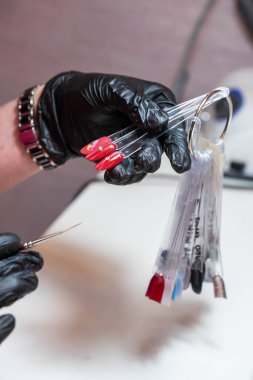 Güzellik salonunda bir müşterisi olan usta manikür ve pedikür dolabında jel rengini seçiyor. Müşteri seçimi için çok renkli oje paletinde farklı oje renkleri var. Tırnak sanatı 