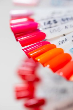 Tırnak cilası örnekleri farklı renklerde. Uç kısımlarda. Müşterinin seçimi için çok renkli oje paleti. Çivi tasarım çarkı. Güzellik salonunda manikür için takma tırnaklar. Beyaz arkaplanda metin için boşluk kopyala