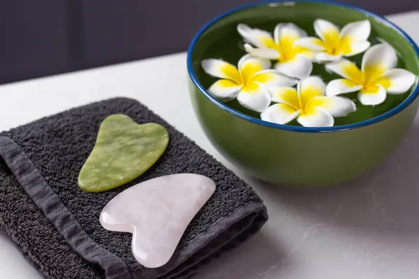Plumeria çiçekleriyle harika bir spa kompozisyonu. Yüz silindiri ve Guasha masaj aleti. Çin Gua Sha masaj aletleri.