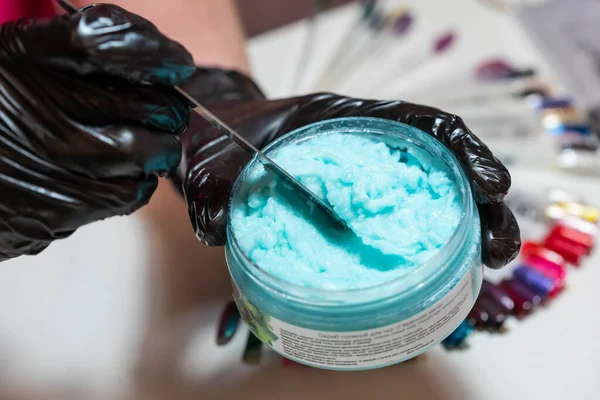 Master mixes blue salt scrub for pedicure and manicure in beauty salon